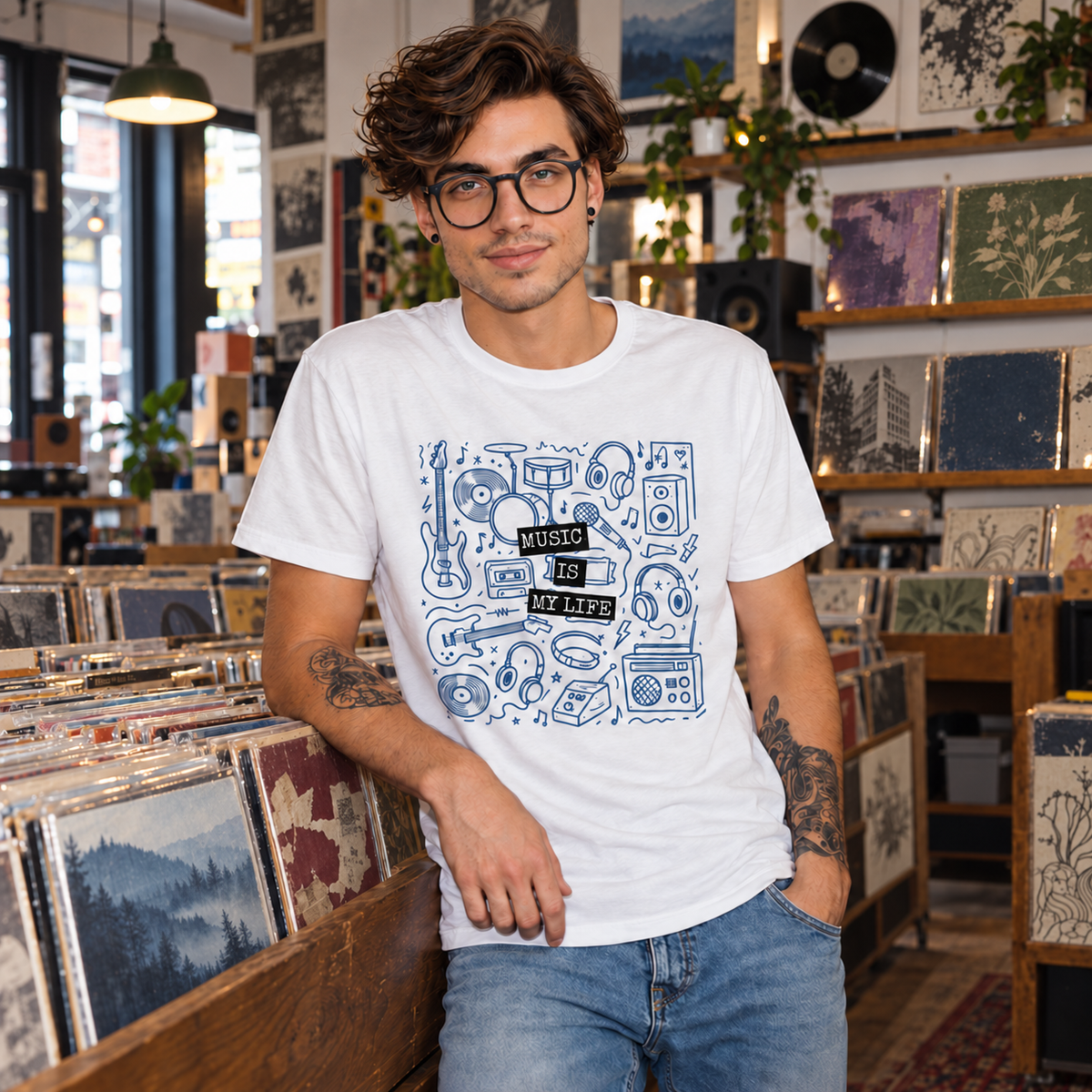 A man wearing a white graphic t-shirt with blue musical instrument illustrations and the text 'MUSIC IS MY LIFE' standing in a record store.