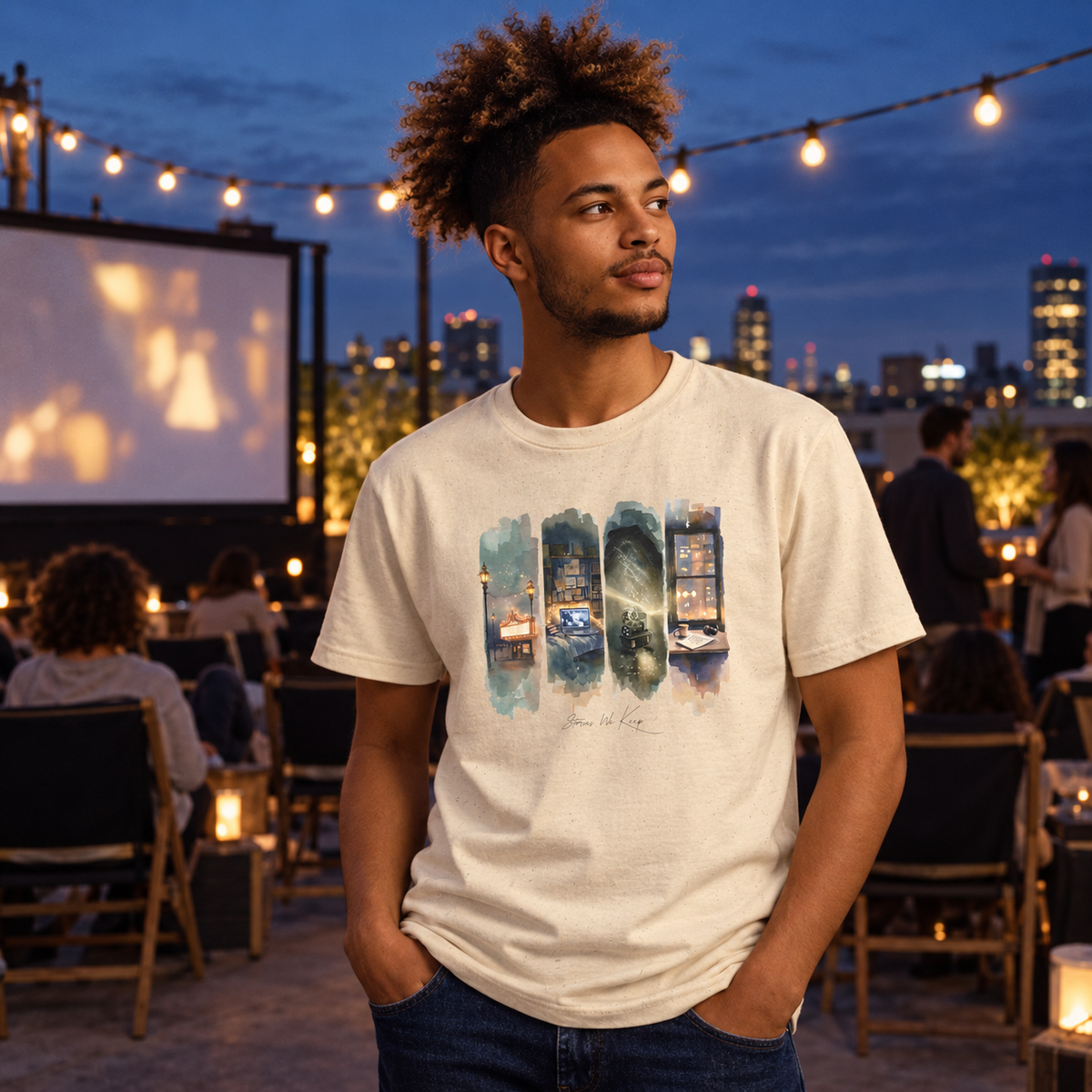 A man wearing a cream-colored graphic t-shirt with slogan 'Stories We Keep' - ideal film lover gift shirt, standing on an outdoor rooftop at dusk with string lights and a city skyline in the background.