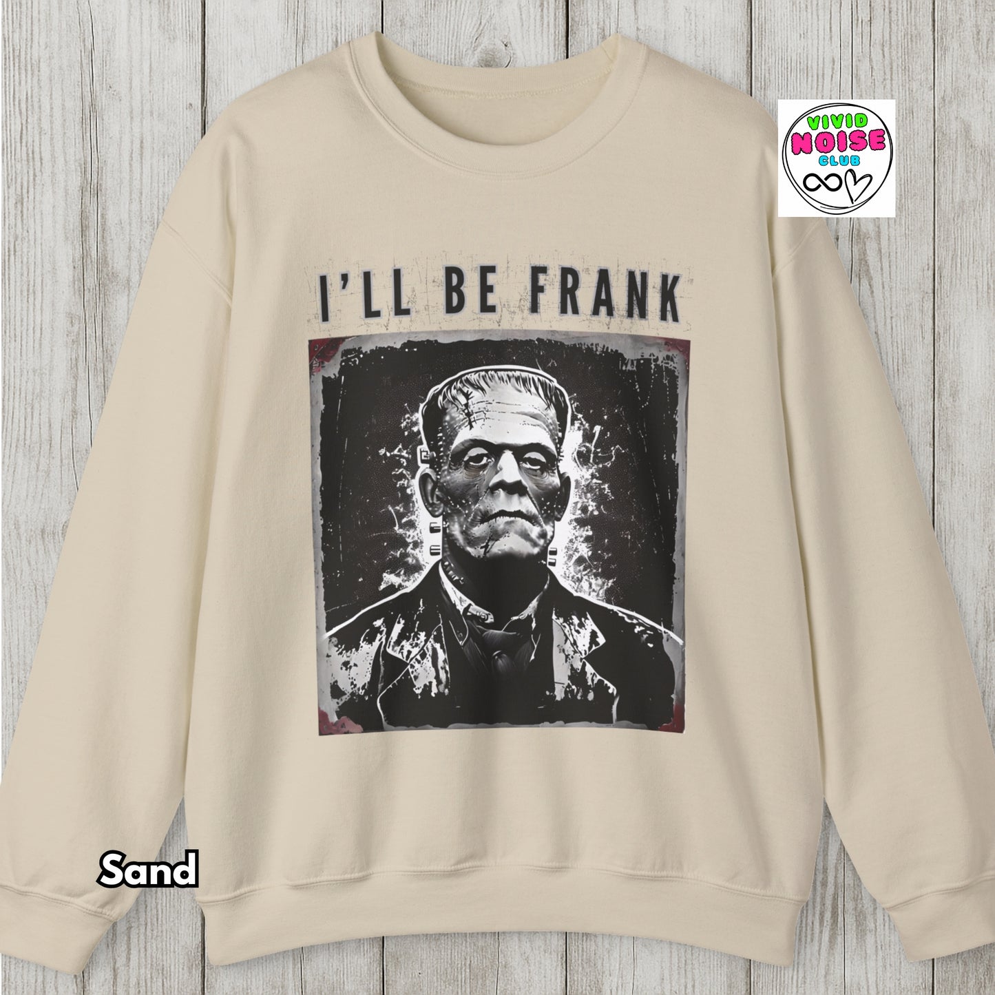 Beige sweatshirt with Frankenstein graphic and 'I'll Be Frank' text on a wooden surface.