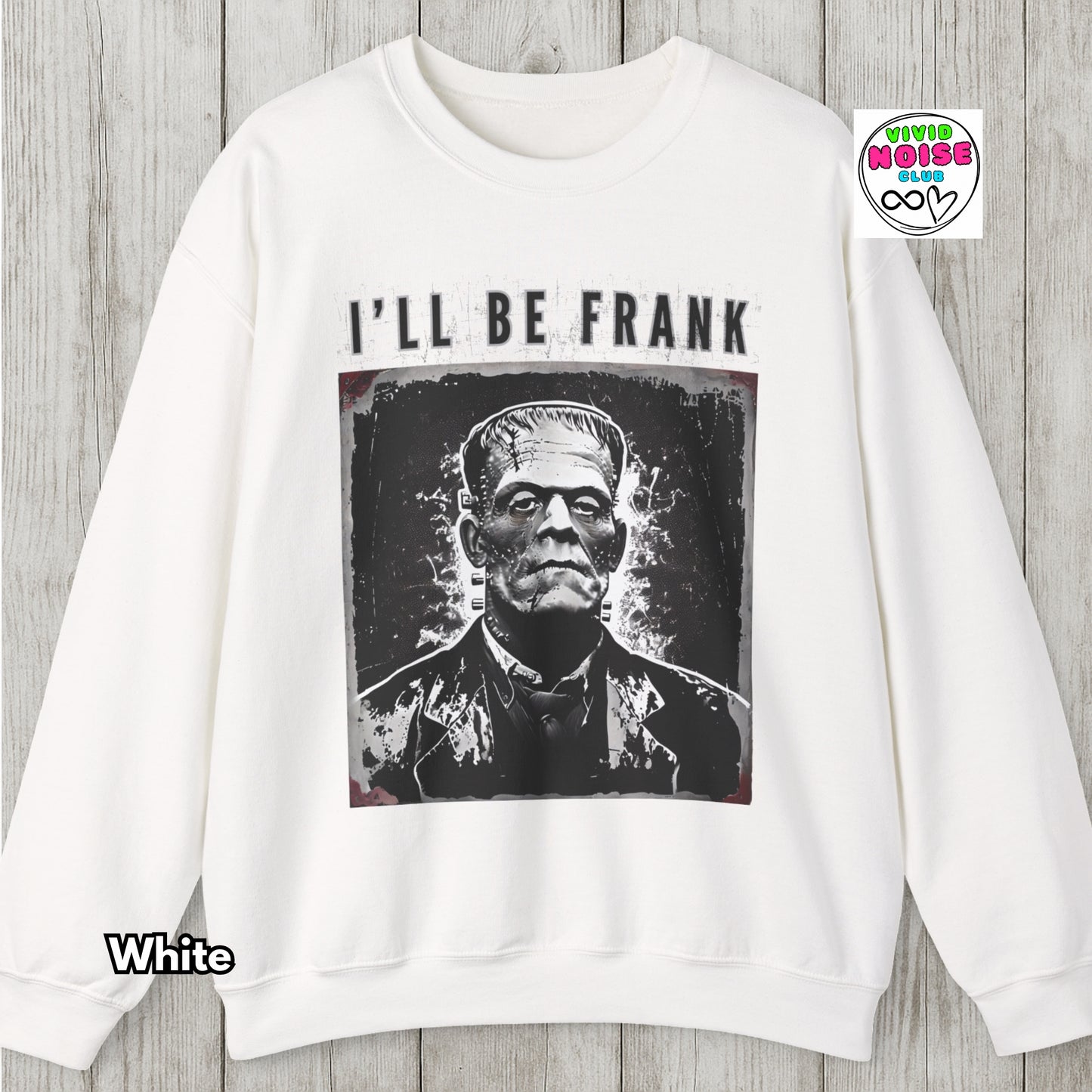 White sweatshirt with a graphic of Frankenstein and text 'I'll Be Frank' on a wooden surface.