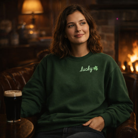 Woman wearing a green sweatshirt with 'Lucky' and a shamrock, sitting in a cozy room with a fireplace.