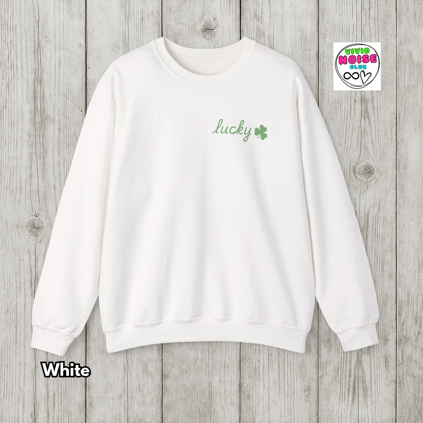 White sweatshirt with 'lucky' and clover design on a wooden background