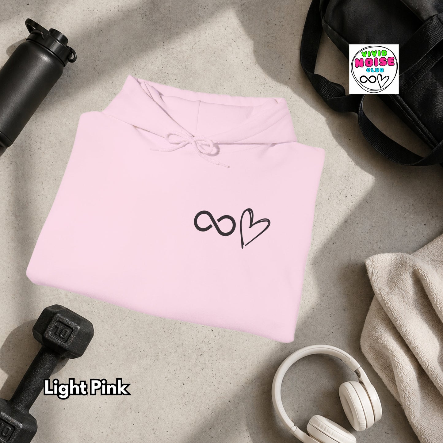 Light pink hoodie with a black heart design on a gray surface with gym items.