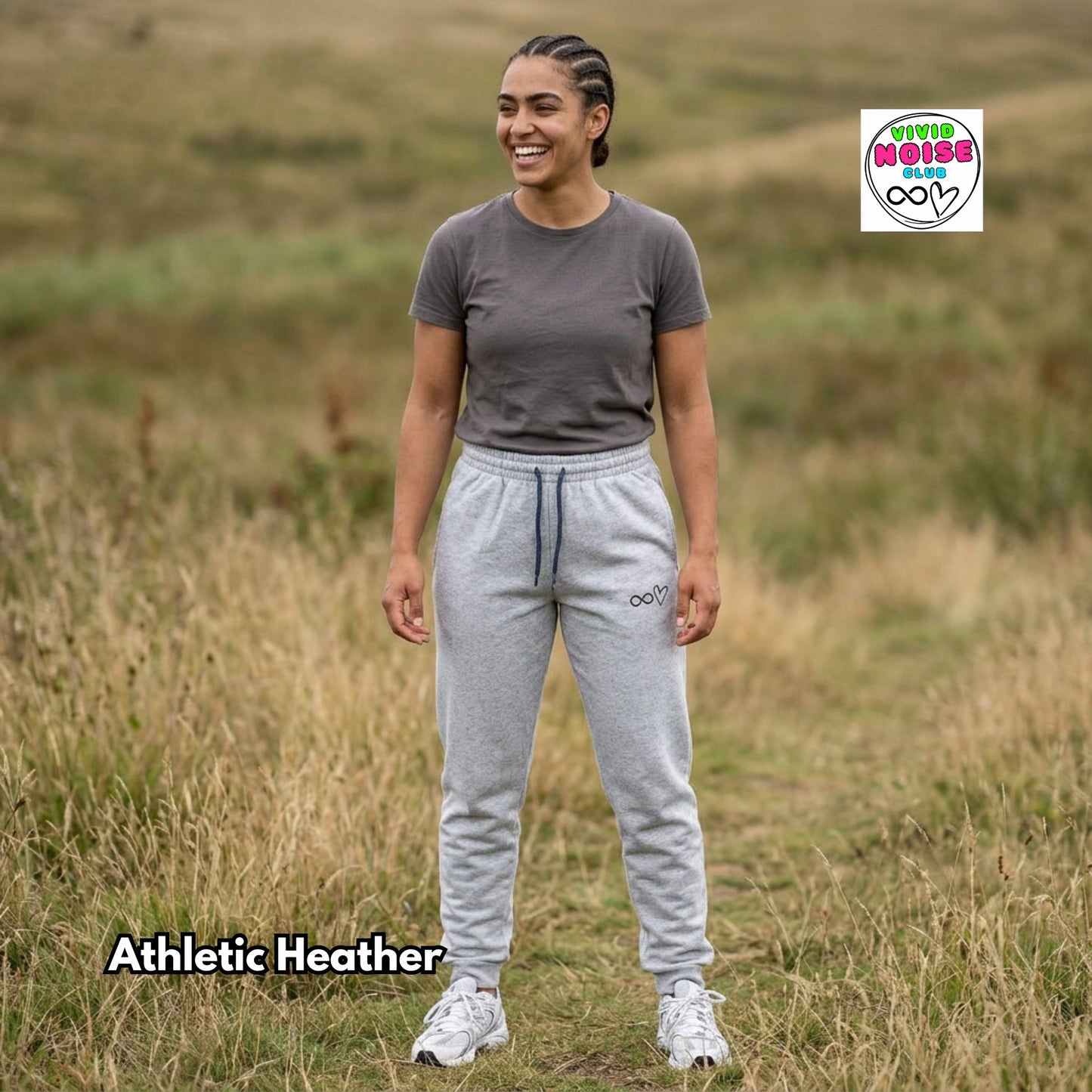 Person wearing athletic heather pants and a gray shirt in a grassy field with Vivid Noise logo.