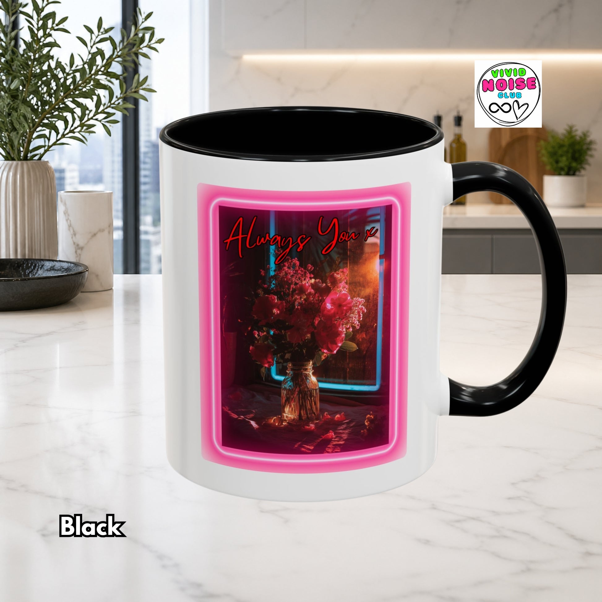White mug with black handle and interior, featuring a pink frame and floral design on a kitchen counter.
