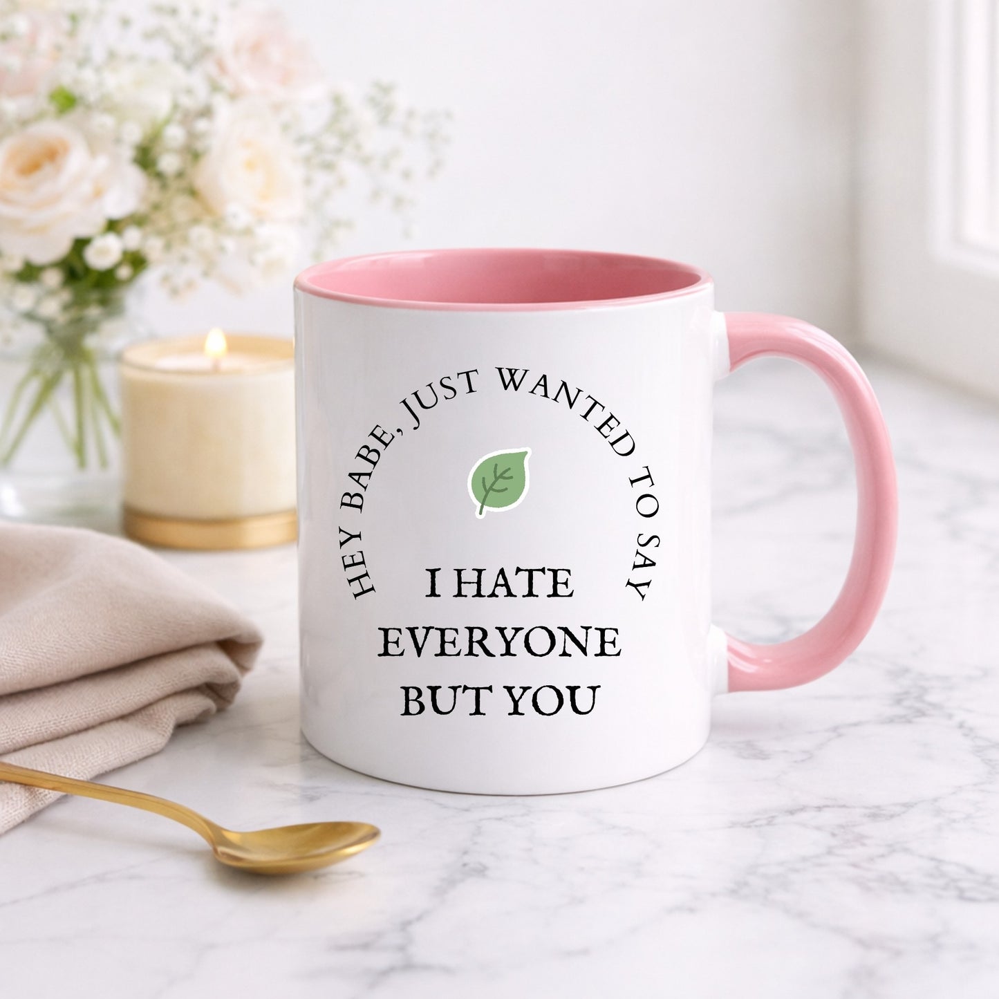 White mug with pink interior and handle on a marble surface with flowers and candle in the background