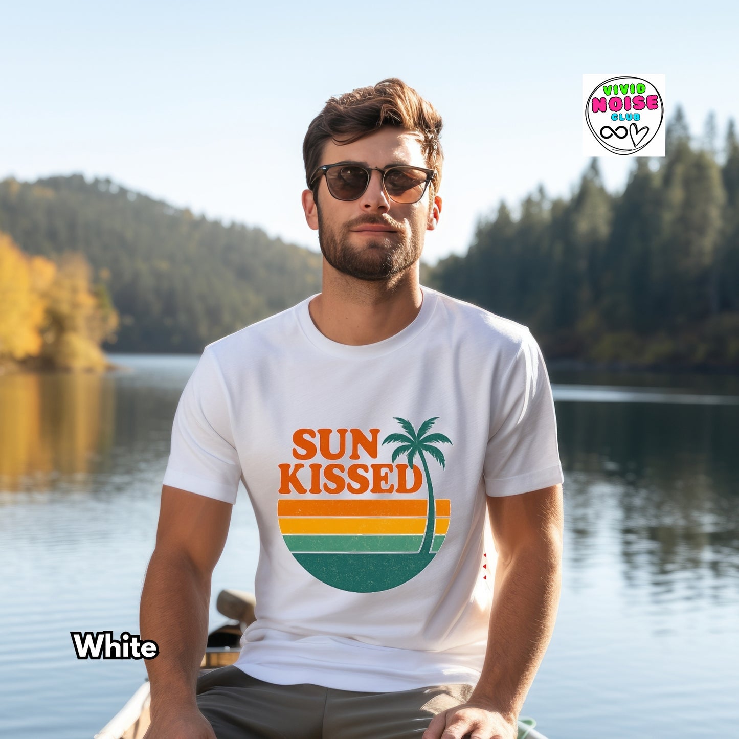 Man wearing a 'Sun Kissed' t-shirt sitting in a boat on a lake with trees in the background
