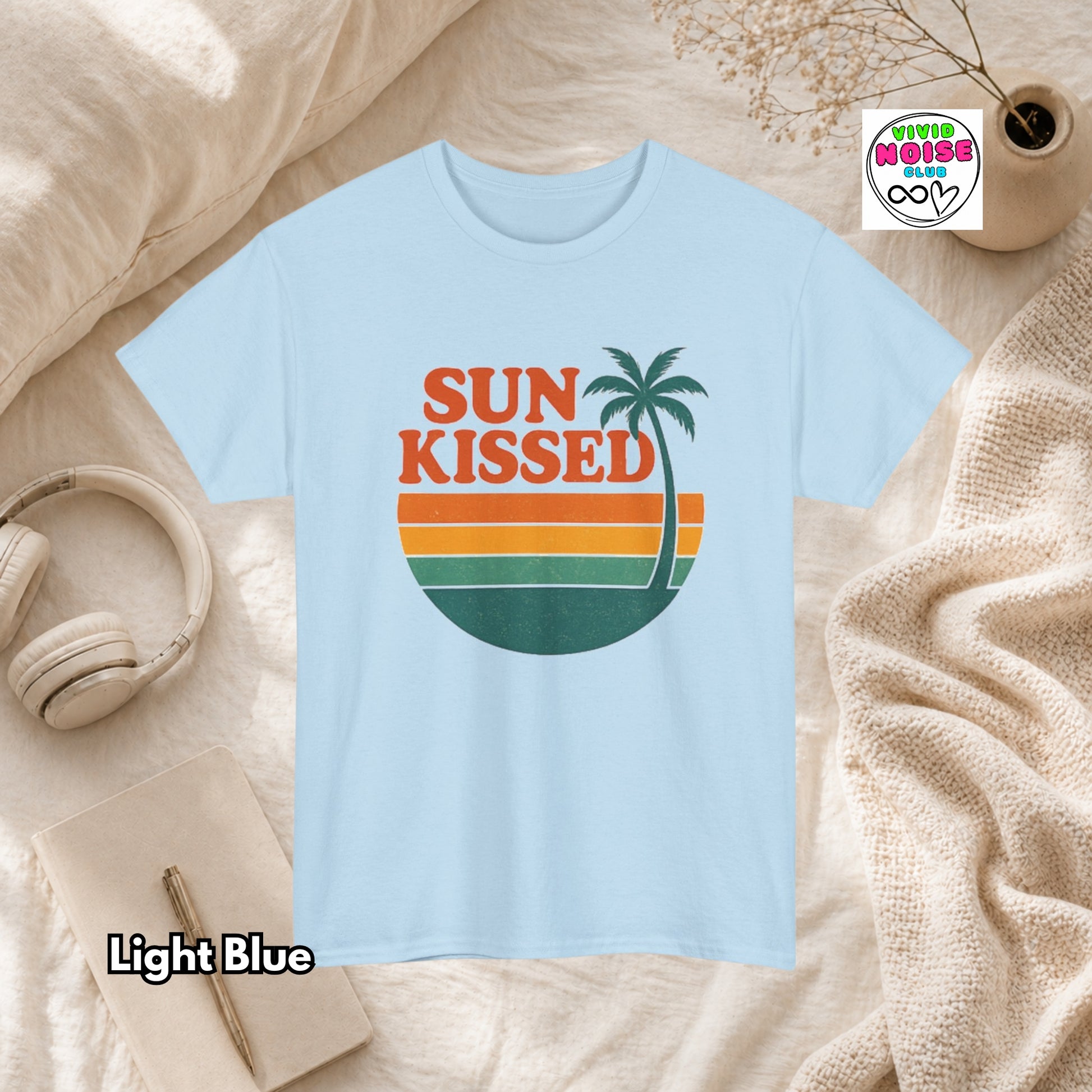Light blue t-shirt with 'Sun Kissed' design on a beige surface