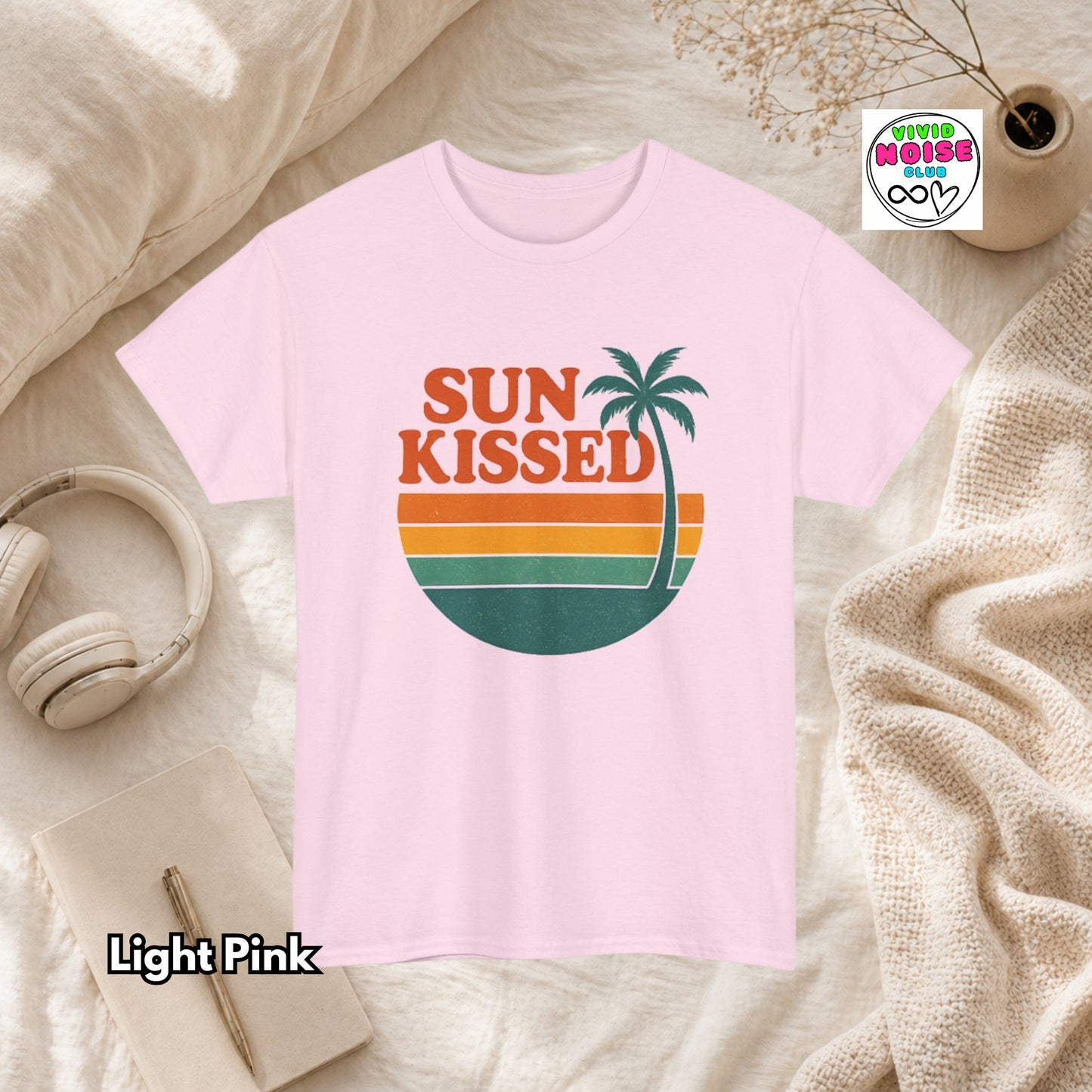 Light pink t-shirt with 'Sun Kissed' design on a textured surface with accessories.