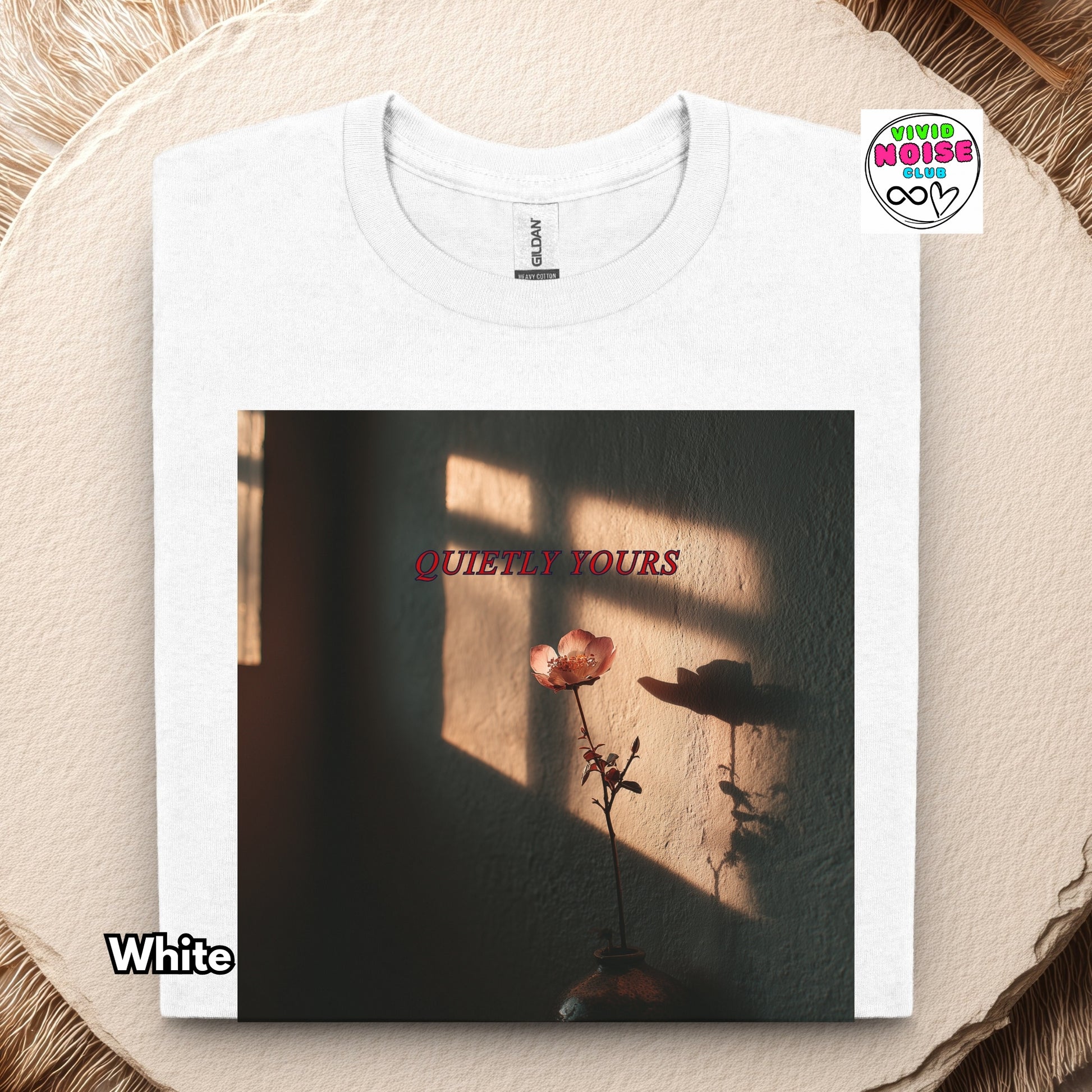 White t-shirt with a printed design of a flower and text Quietly Yours on a textured surface