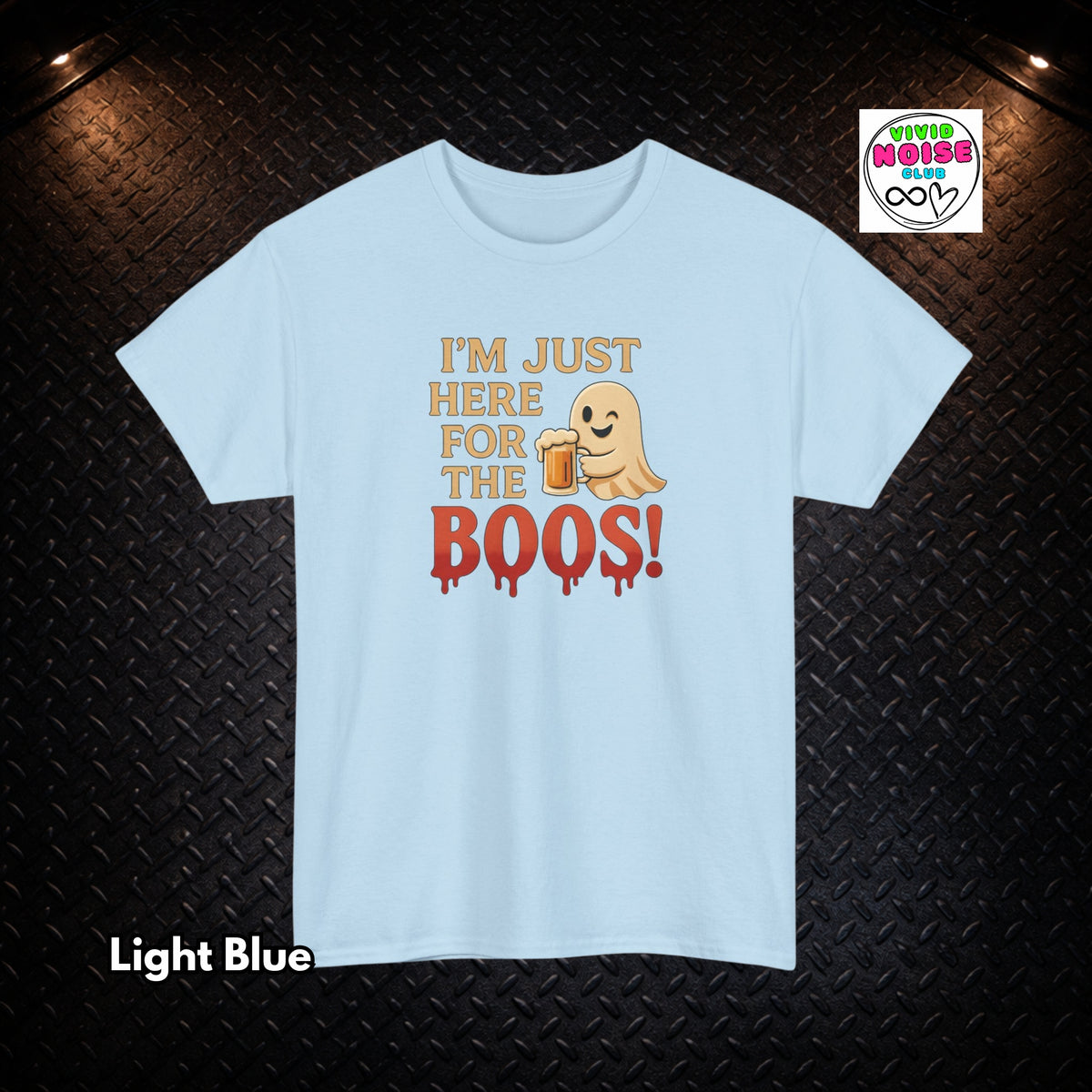 A light blue short-sleeve t-shirt with a graphic print that reads 'I'M JUST HERE FOR THE BOOS!' in gold and red, featuring a small cartoon ghost holding a beer mug. The shirt is displayed flat against a dark textured diamond plate background, with a 'Tired of Being Noob' logo in the top right corner and 'Light Blue' text in the bottom left.