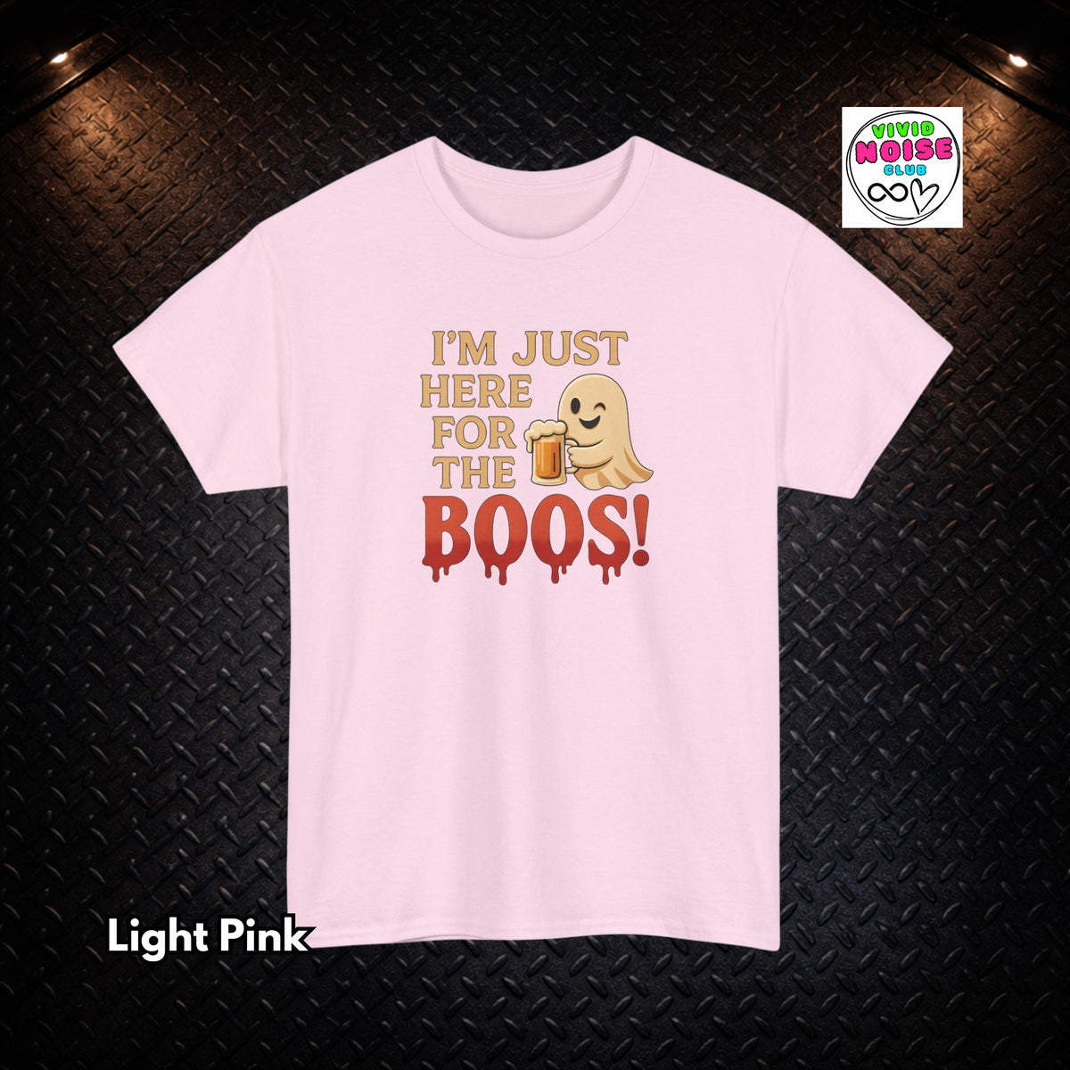 A light pink short-sleeve t-shirt with a humorous graphic on a black diamond plate background. The graphic features the text 'I'M JUST HERE FOR THE BOOS!' in tan and dripping red letters, alongside a cartoon ghost holding a beer mug.