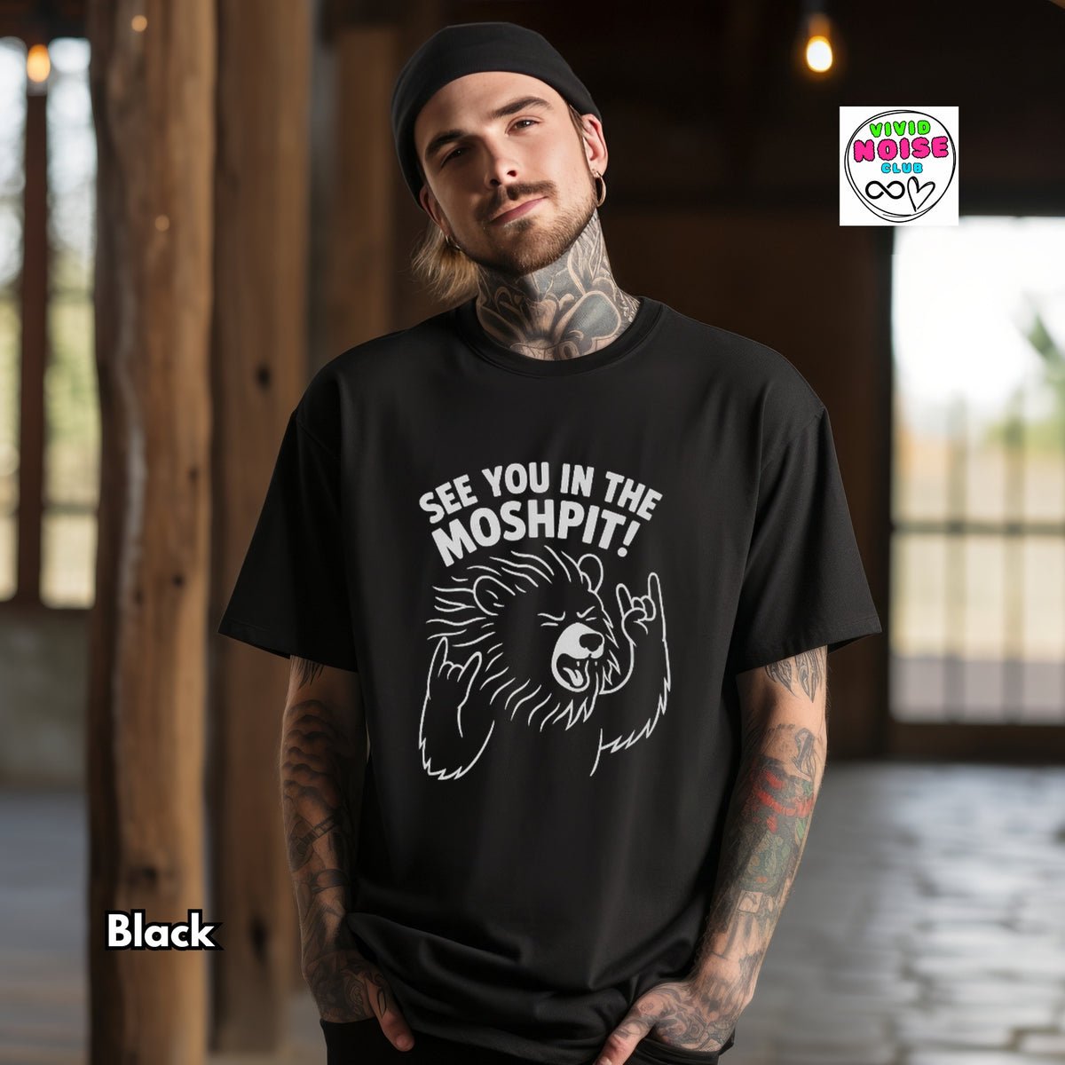 A man wearing a black t-shirt with a white graphic of a bear making a hand gesture and the text 'SEE YOU IN THE MOSHPIT!'. The background is a rustic indoor setting with wooden pillars.