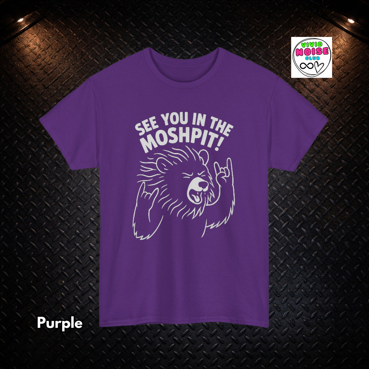 A purple short-sleeve t-shirt with a white graphic of a bear making a hand gesture and the text 'SEE YOU IN THE MOSHPIT!' on the front, displayed against a black diamond plate background with a 'Vivid Noise Club' logo in the top right corner.