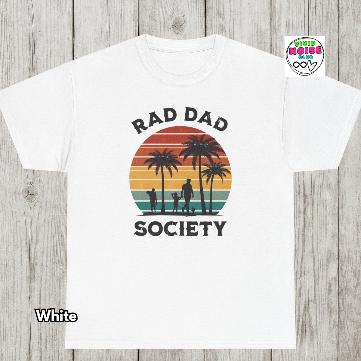 A white t-shirt with a retro sunset graphic featuring palm trees and a family silhouette, with the text 'RAD DAD SOCIETY' printed on the front. The t-shirt is displayed flat against a gray wood-plank background, with a 'White' color label in the bottom-left corner and a 'Vivid Noise Club' brand logo in the top-right corner.