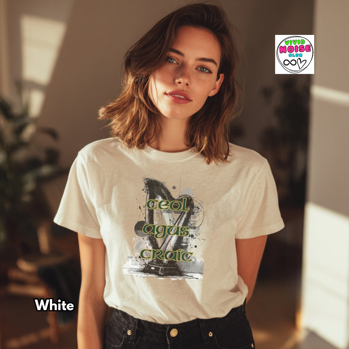 A woman wearing a white graphic t-shirt with a black and green print that reads 'Ceol Agus Craic', set in a warm, sunlit indoor environment. A 'Vivid Noise Club' logo is visible in the top right, and 'White' is written in the bottom left.