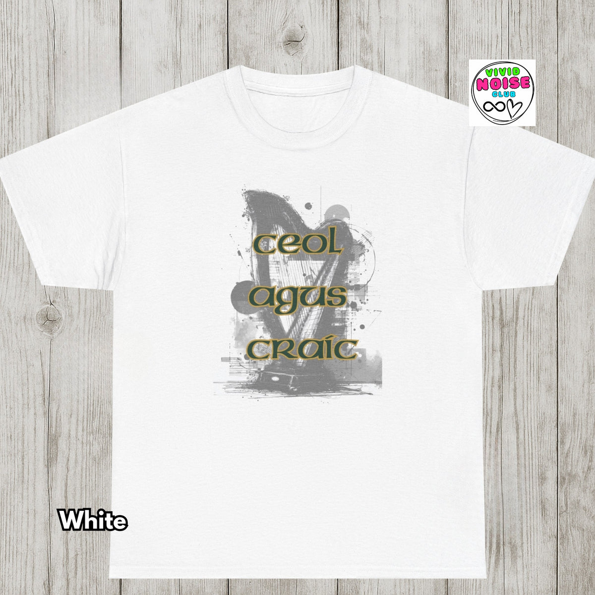 A white short-sleeve crewneck t-shirt laid flat on a light gray wood plank background. The shirt features a central graphic with the words 'Ceol Agus Craic' in olive green.