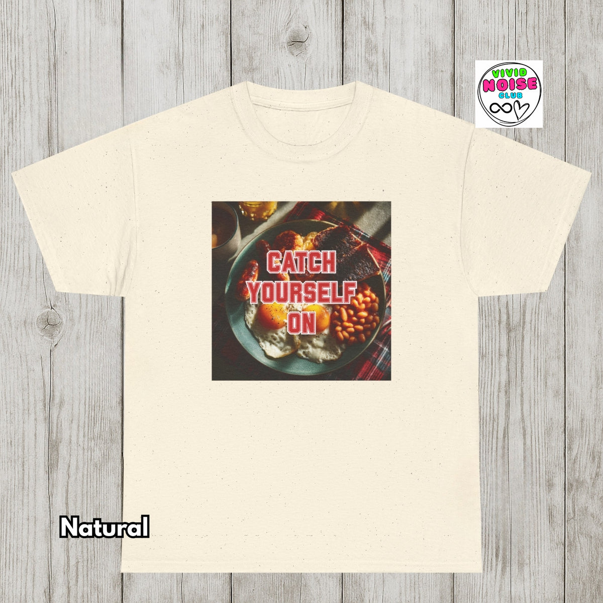 A cream-colored short-sleeve t-shirt with a graphic print of a plate of food with the text 'CATCH YOURSELF ON' in red. The t-shirt is displayed on a gray wood-plank background, with a 'Natural' color label at the bottom left and a 'Other Noise' logo at the top right.