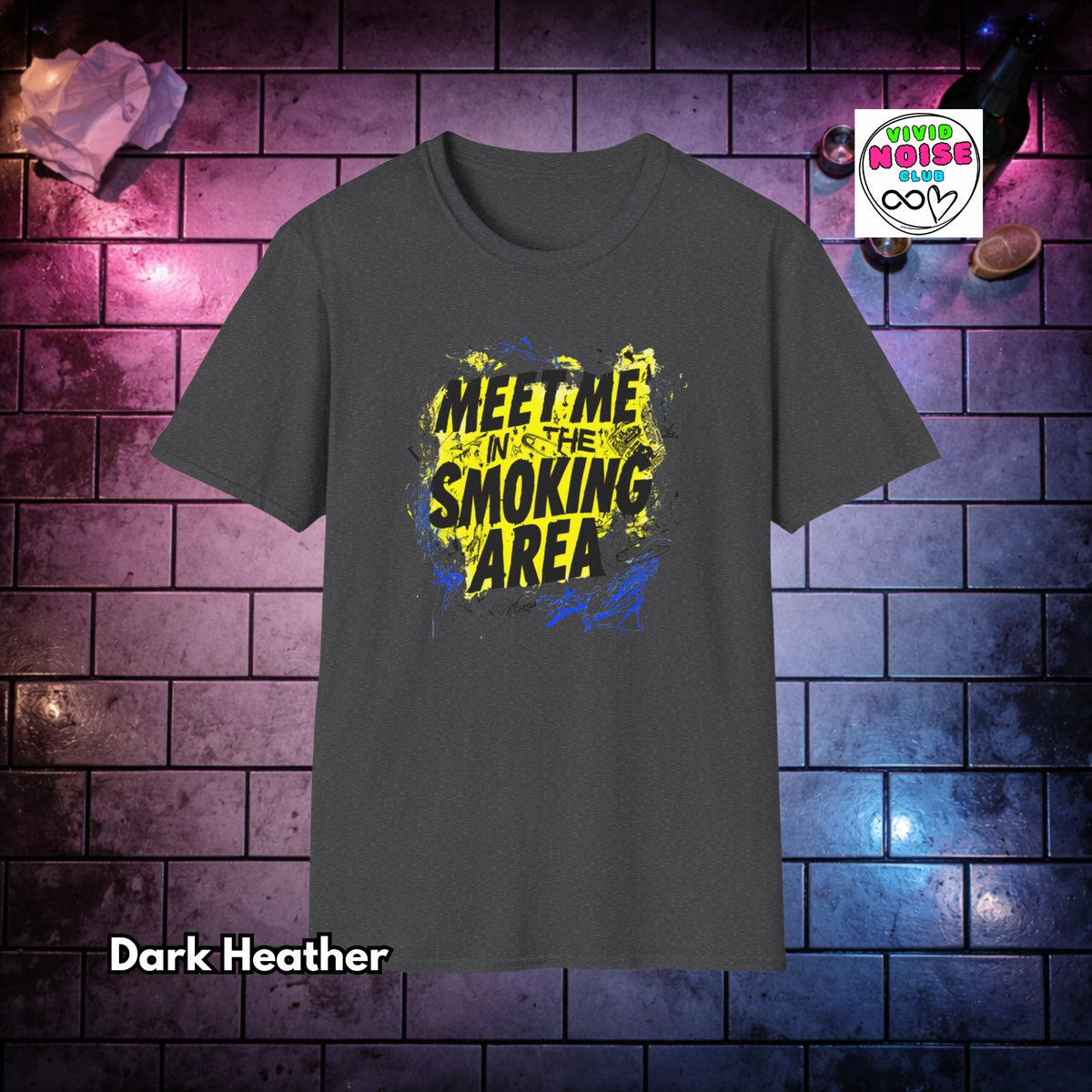 A dark heather gray t-shirt with a graphic print reading 'MEET ME IN THE SMOKING AREA' in yellow and black over a blue paint-splatter background. The shirt is displayed against a purple and blue-lit brick wall backdrop, with a 'Vivid Noise Club' logo in the top right and 'Dark Heather' text in the bottom left.