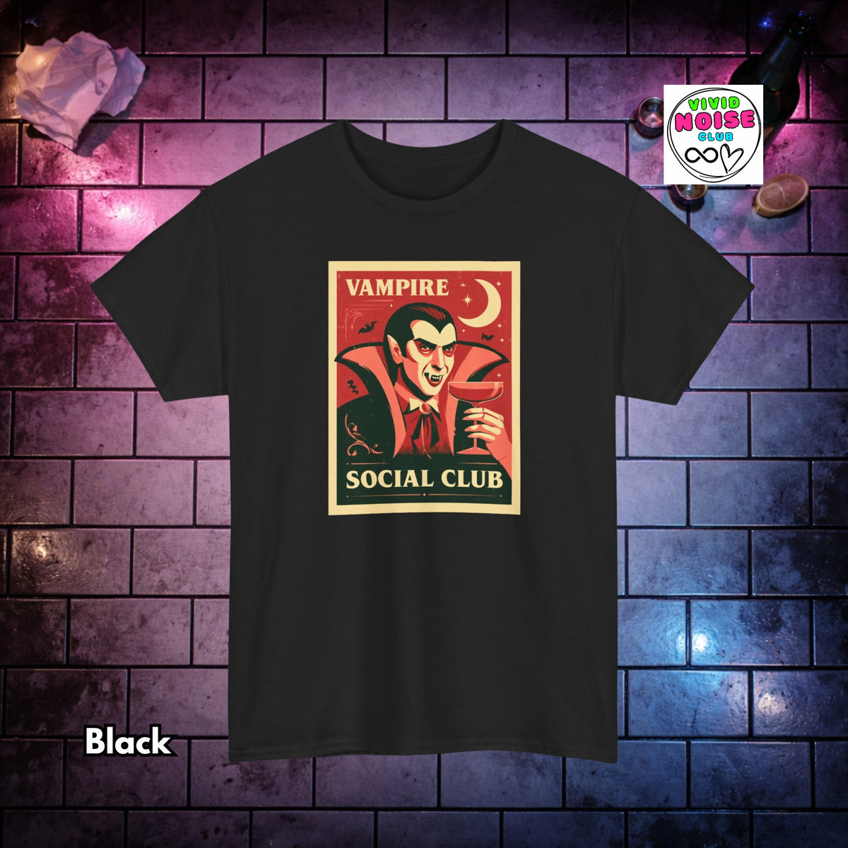 A black short-sleeve t-shirt with a vintage-style graphic print of a vampire holding a glass, with the text 'VAMPIRE SOCIAL CLUB' in a cream and red poster design. The shirt is displayed against a dark brick wall background with purple and blue lighting, with a 'Vivid Noise Club' brand logo in the top right and a 'Black' color label in the bottom left.