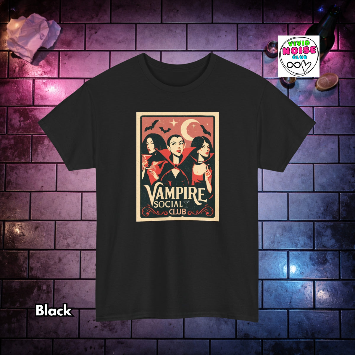 A black short-sleeve t-shirt with a vintage-style graphic print reading 'Vampire Social Club' featuring three vampire characters under a crescent moon. The shirt is displayed against a dark brick wall background with purple and blue lighting, with a 'Vivid Noise Club' brand logo in the top right corner.