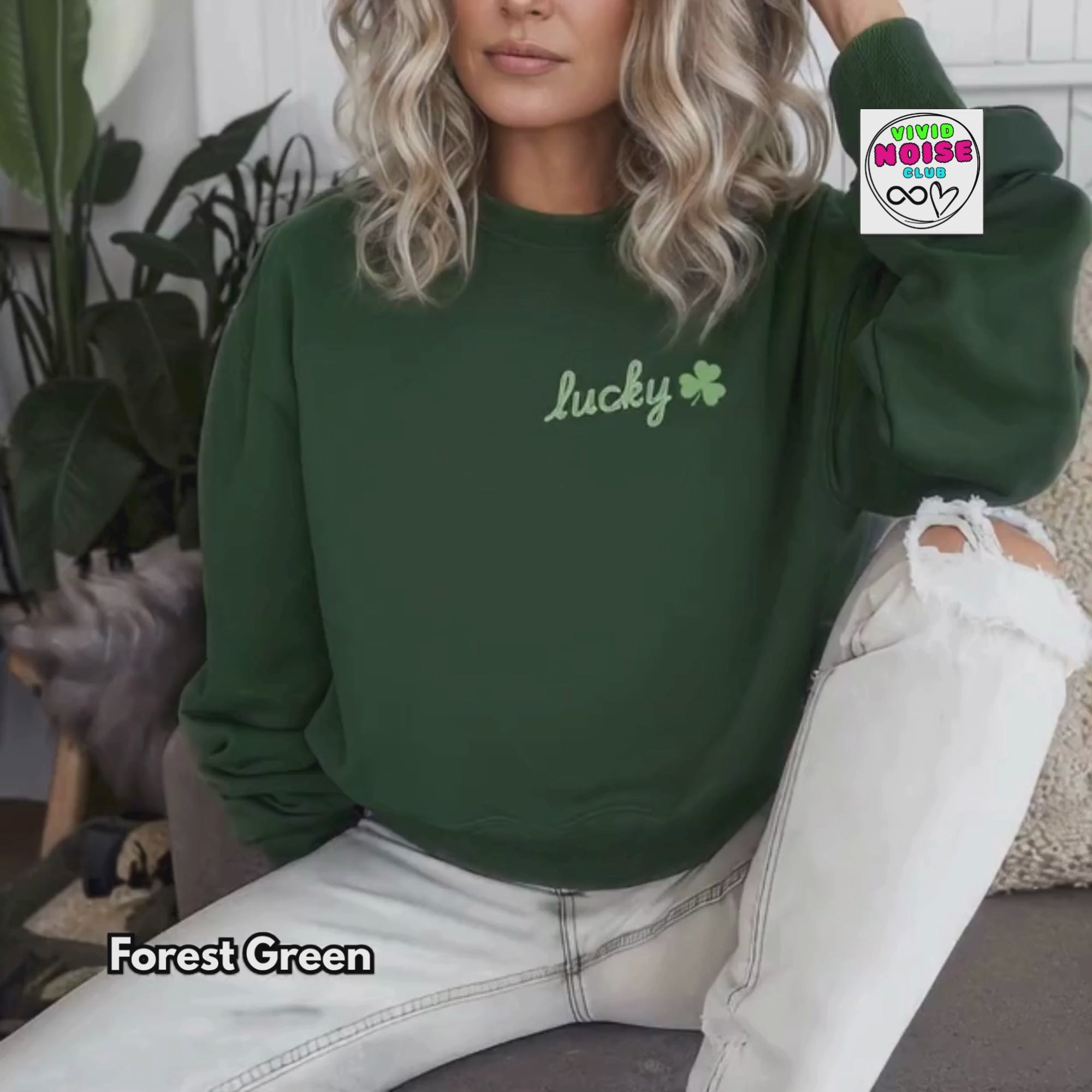 Video of models wearing a dark green Lucky shamrock sweatshirt in a cosy Irish pub setting with a pint on the table and available variations.