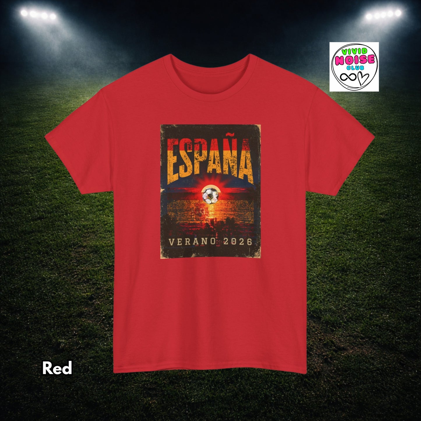 A red short-sleeve t-shirt with a distressed graphic on the chest reading 'ESPAÑA VERANO 2026' over a soccer-themed design. The shirt is displayed on a dark green soccer field background with stadium lights shining down, and a 'Tienda No.